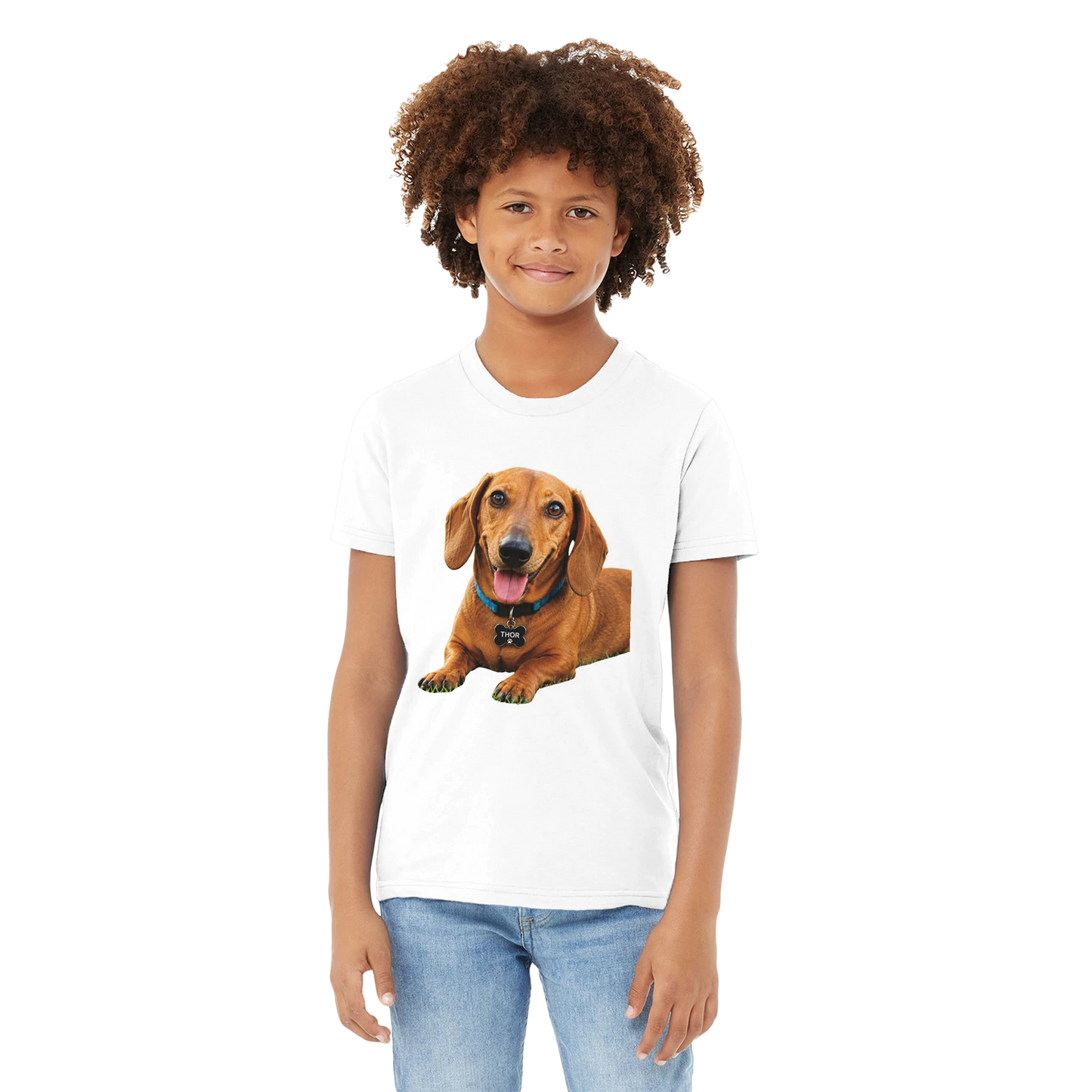 A child model wearing a white short-sleeve crewneck t-shirt with a graphic print of a brown dachshund dog on the front, paired with blue jeans, set against a plain white background.