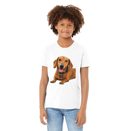 A child model wearing a white short-sleeve crewneck t-shirt with a graphic print of a brown dachshund dog on the front, paired with blue jeans, set against a plain white background.